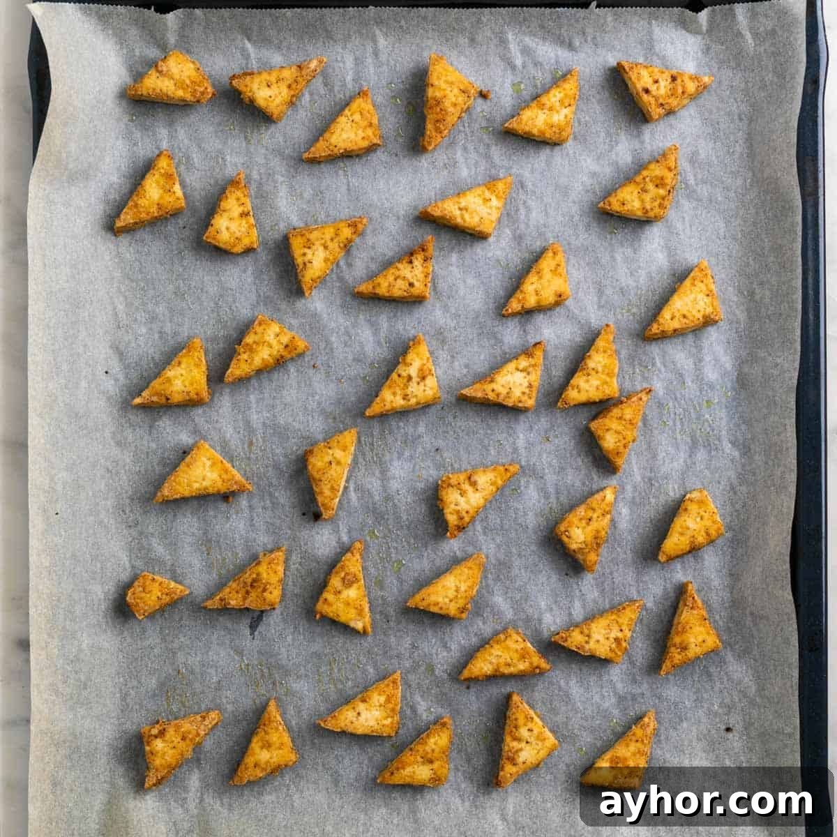 Grilled BBQ Tofu Recipe: Smoky, Glazed Plant-Based Dish 9 Baked tofu triangles on a baking sheet