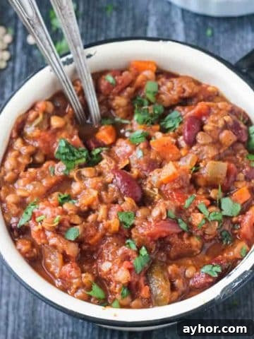 Pot of vegan pumpkin chili with two spoons.
