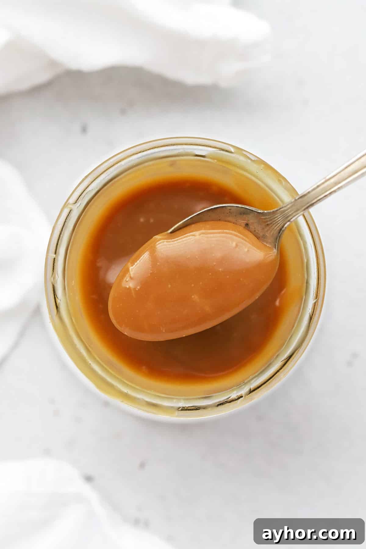Homemade Caramel Sauce Recipe — Rich, Smooth & Pourable 2 Scooping a spoonful of easy caramel sauce