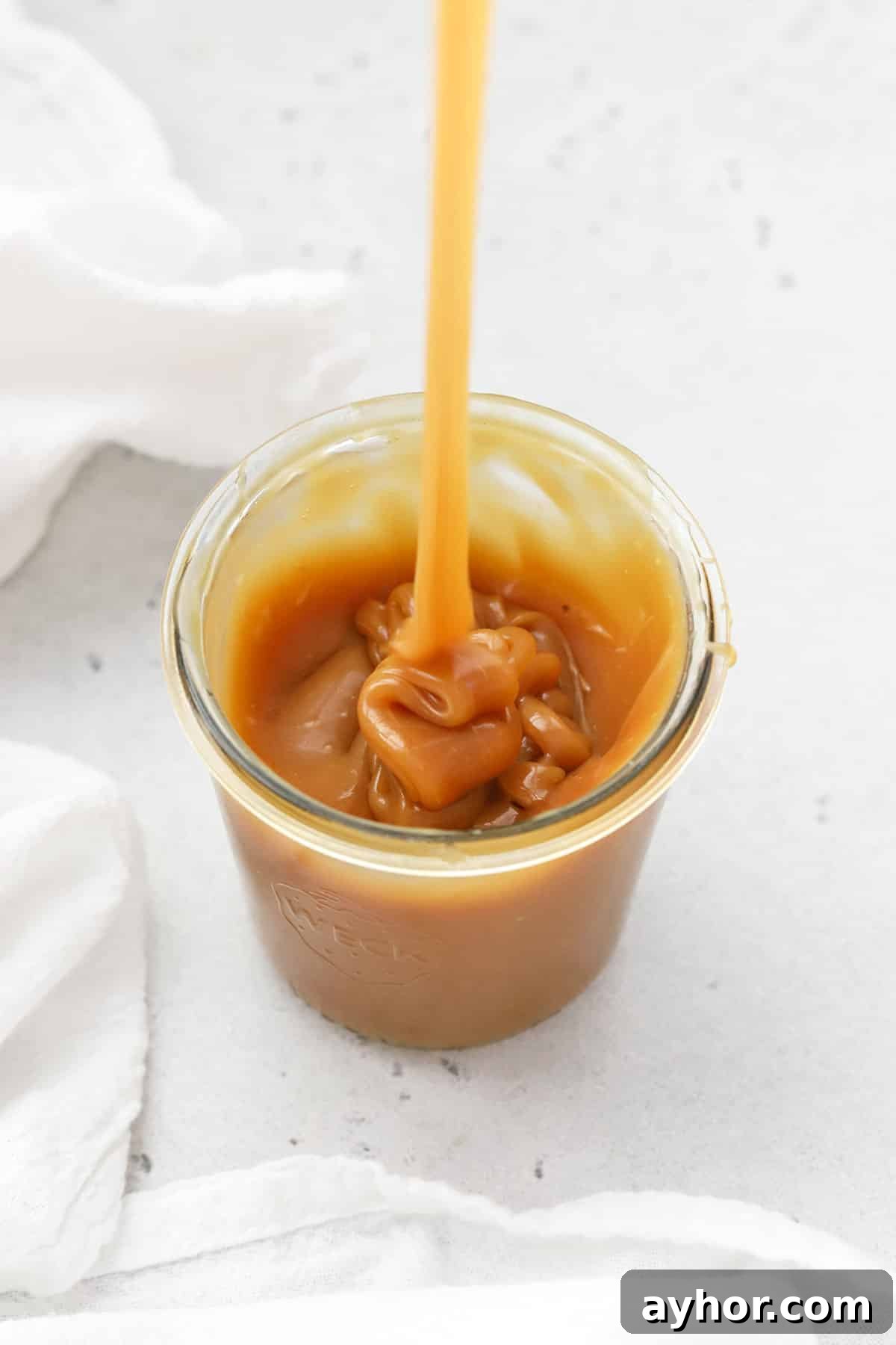 Homemade Caramel Sauce Recipe — Rich, Smooth & Pourable 7 Pouring thick homemade caramel sauce into a jar