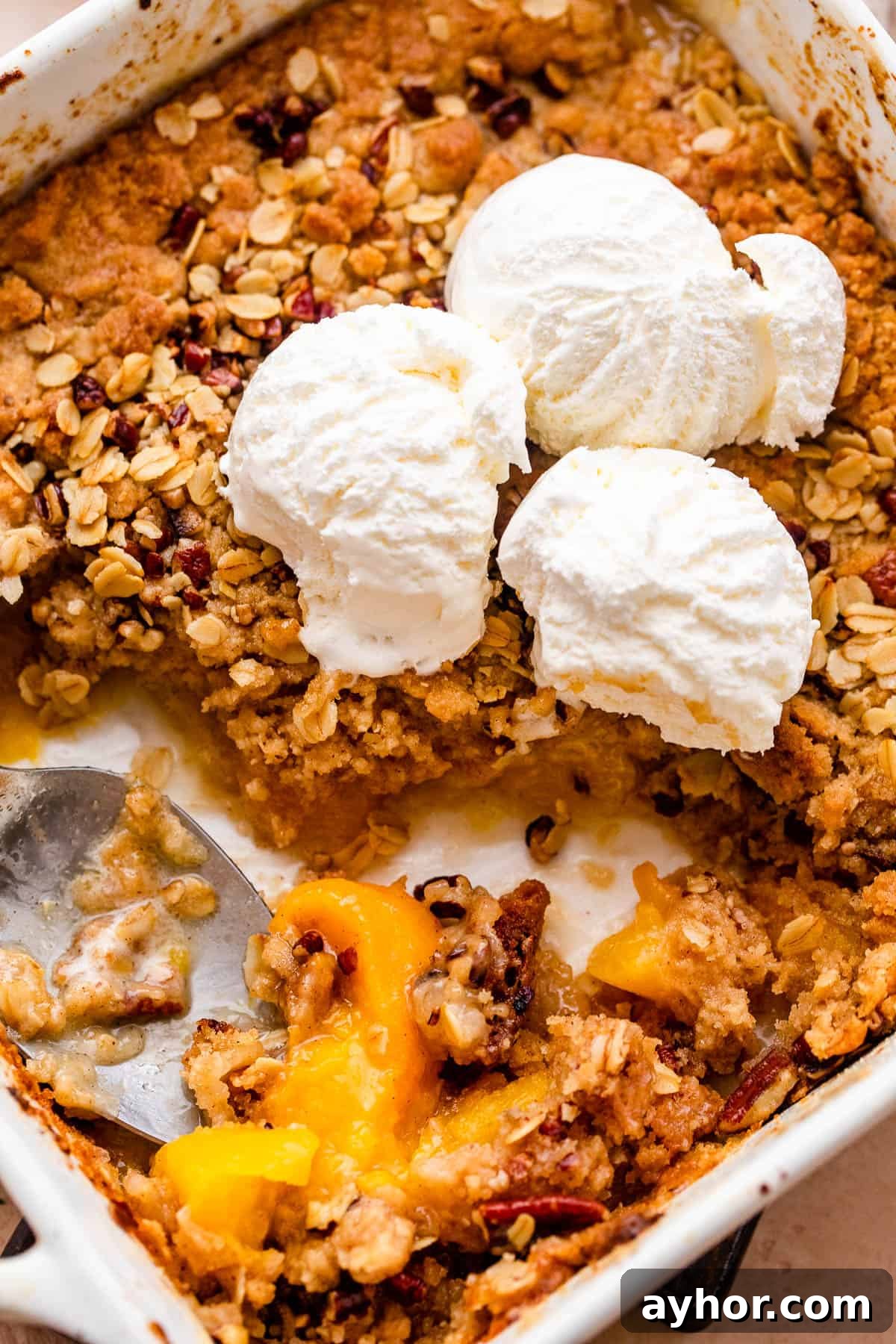 Perfect Peach Crisp Recipe for Summer Baking 3 peach crisp in a white baking dish topped with scoops of vanilla ice cream