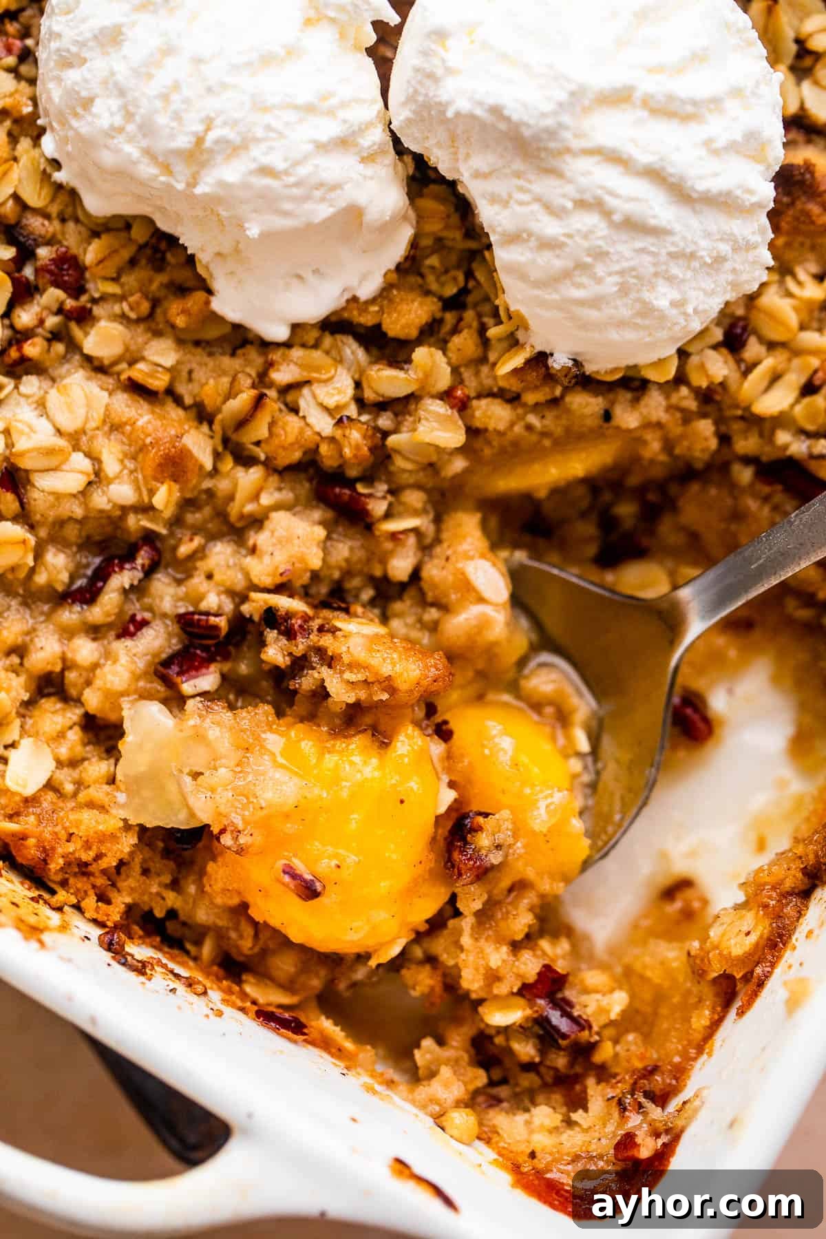 Perfect Peach Crisp Recipe for Summer Baking 6 peach crisp in a white baking dish topped with scoops of vanilla ice cream