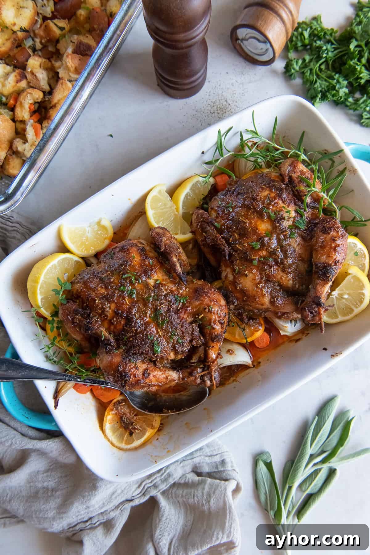 Crispy Roasted Cornish Game Hens with Garlic and Herbs 3 A top down shot of two roasted cornish game hens in a baking dish with a spoon.