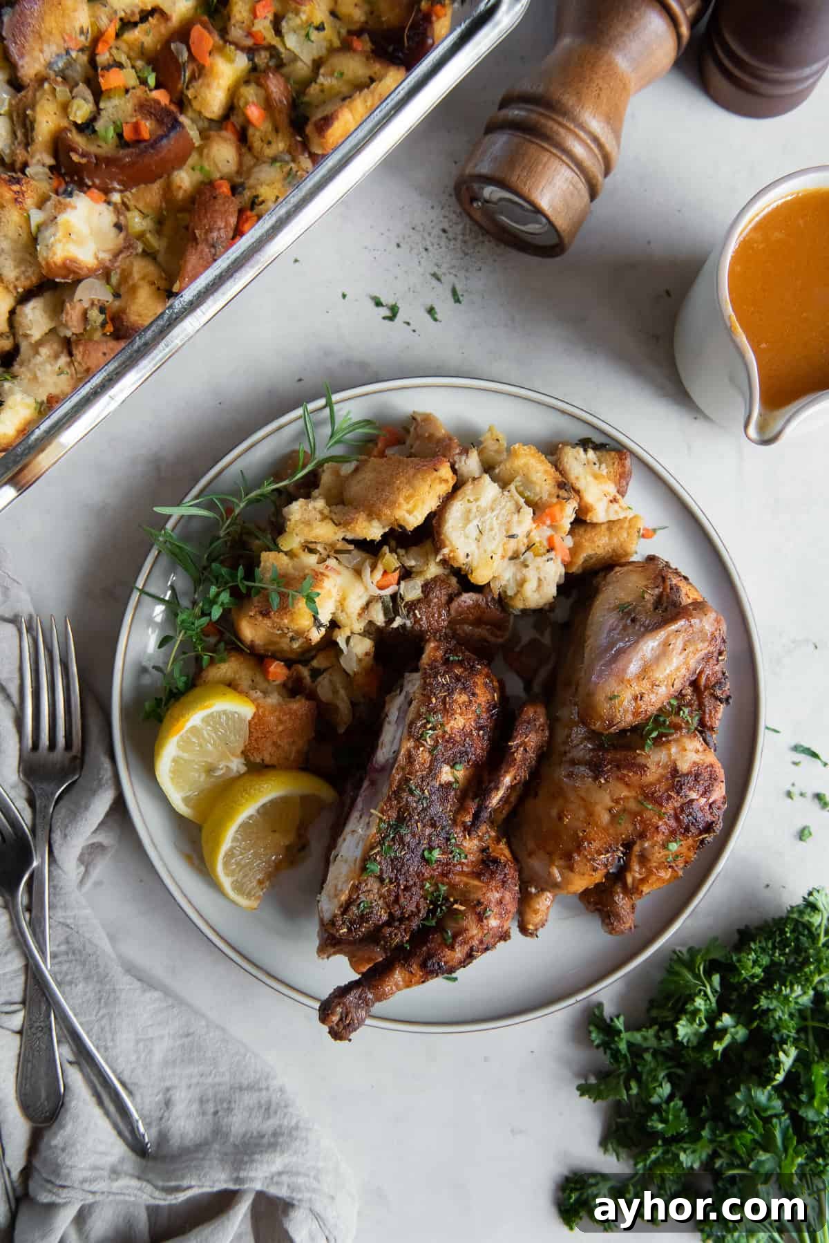 Crispy Roasted Cornish Game Hens with Garlic and Herbs 8 A cornish game hen sliced in half on a plate with stuffing.
