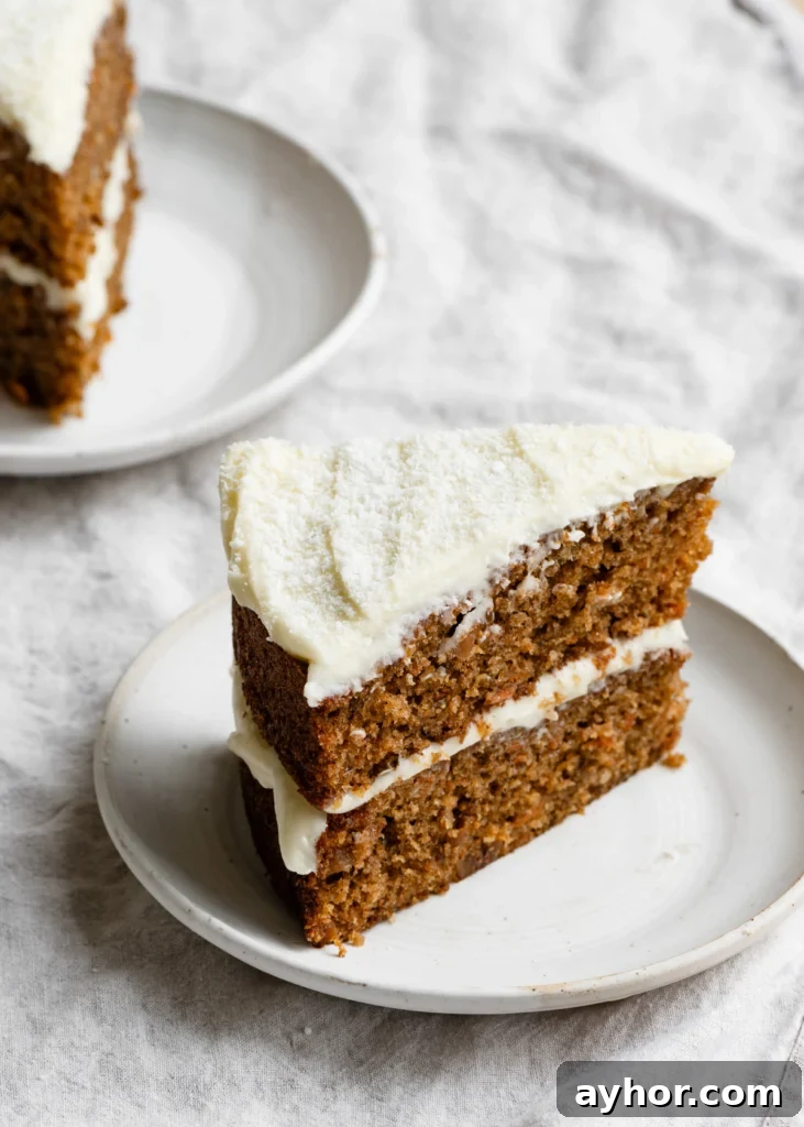 Moist Carrot Cake with Cream Cheese Frosting Recipe 2 Slice of a two layer coconut carrot cake with cream cheese frosting on a plate.
