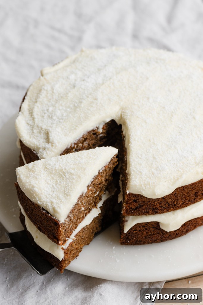 Moist Carrot Cake with Cream Cheese Frosting Recipe 12 A two layer carrot cake with cream cheese frosting on a plate with a slice being pulled away.