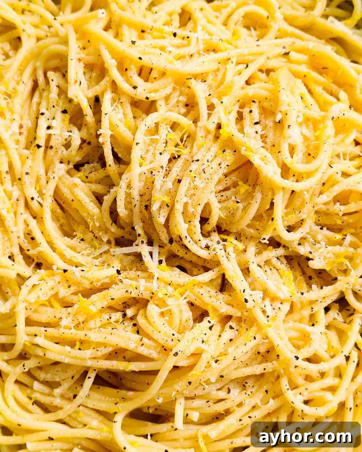 Creamy Lemon Garlic Butter Pasta Recipe for Quick Weeknight Meals 14 Close up of spaghetti topped with parmesan cheese, lemon zest and black pepper