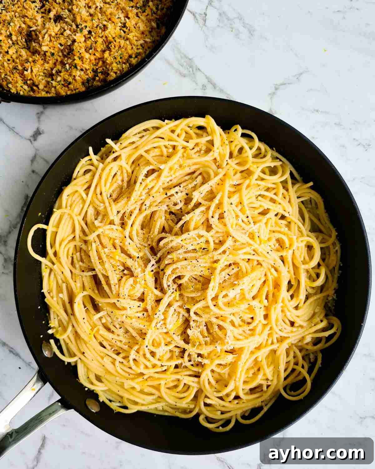 Creamy Lemon Garlic Butter Pasta Recipe for Quick Weeknight Meals 15 Spaghetti in a large frying pan with herbed breadcrumbs in the background