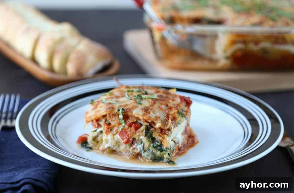 Spaghetti Squash Lasagna Recipe: Low-Carb Cheesy Layered Bake 3 piece of spaghetti squash lasagna on a black and white plate with a whole lasagna and sliced bread in the background.