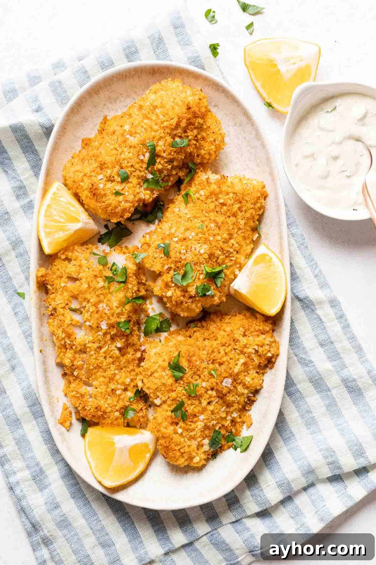 Crispy Panko-Crusted Cod with Lemon Herb Sauce 6 panko crusted cod on oval platter with tartar sauce on the side.