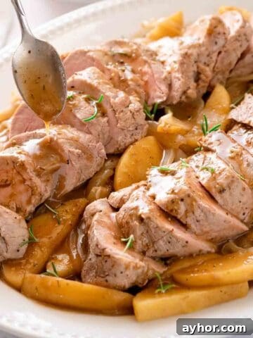 sliced pork tenderloin resting on bed of cooked apples and onions