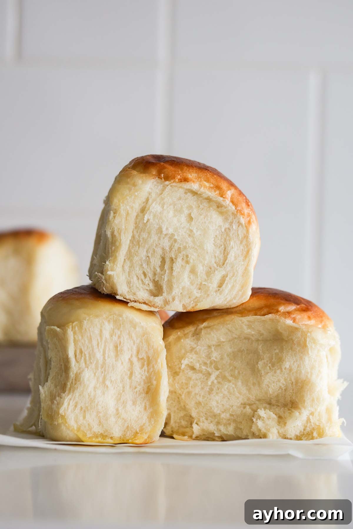 Three sourdough Hawaiian rolls on top of parchment paper.