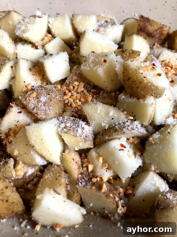 parmesan cheese and spices over potatoes for herb roasted potato recipe
