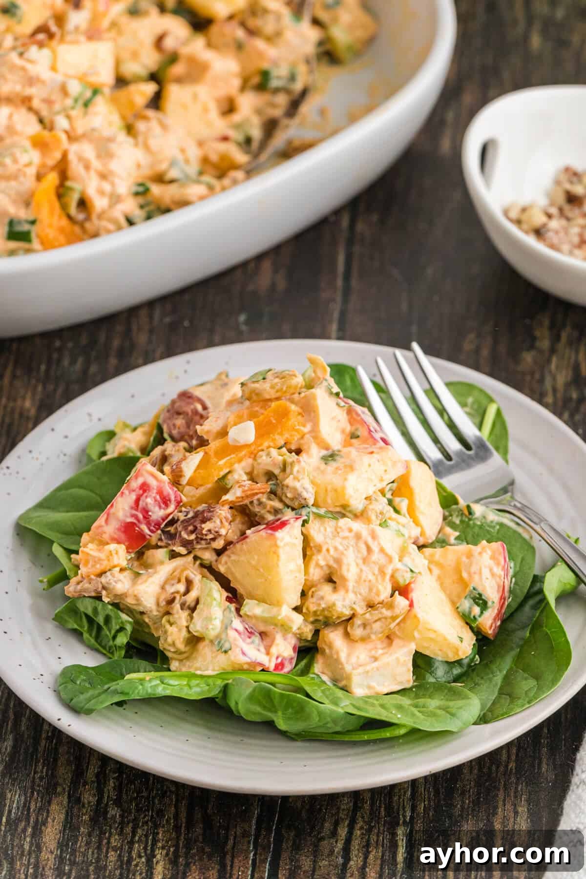 Classic Curried Chicken Salad Recipe for Sandwiches & Lunch 8 Famous curried chicken salad on a bed of spinach on a plate.