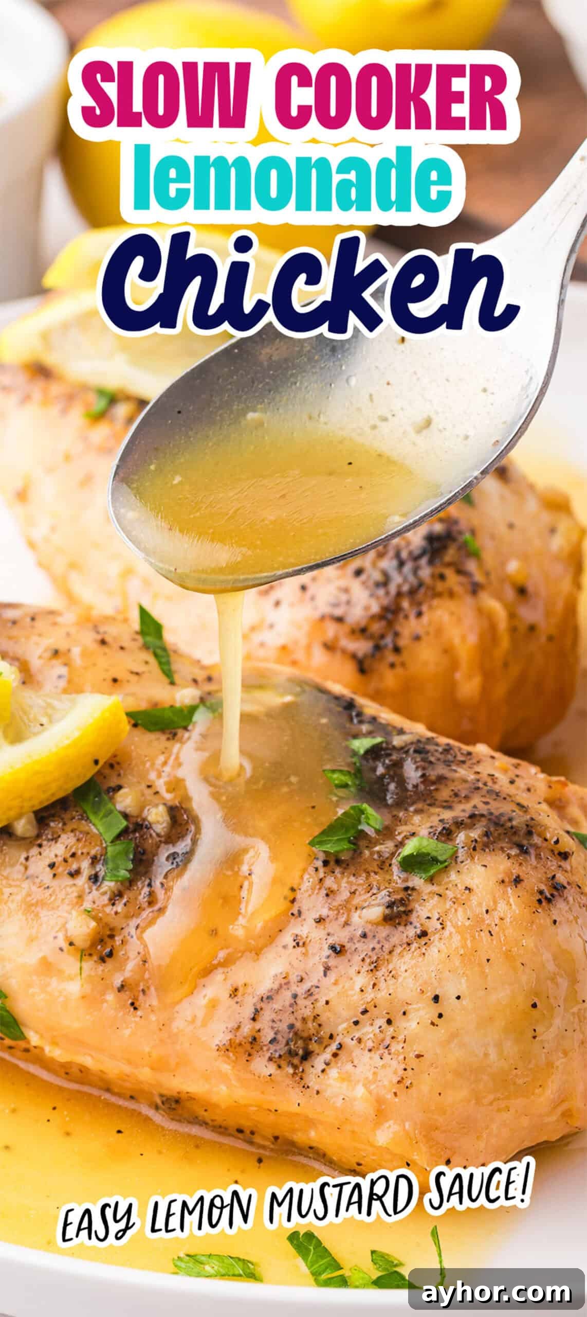 A spoon drizzles lemon mustard sauce over seasoned chicken breasts garnished with lemon slices and herbs.