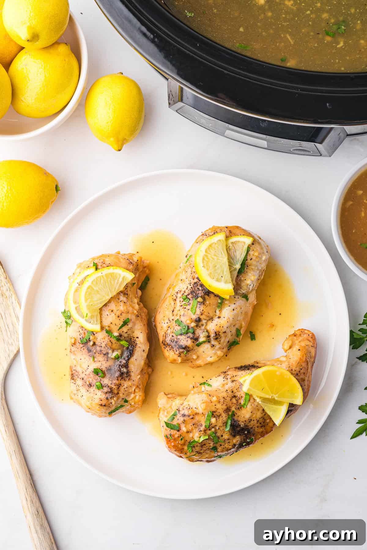 Lemonade chicken breasts garnished with lemon slices on a white plate.