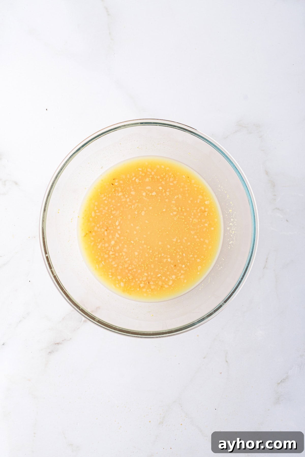 A glass bowl containing a yellow lemonade-based sauce.