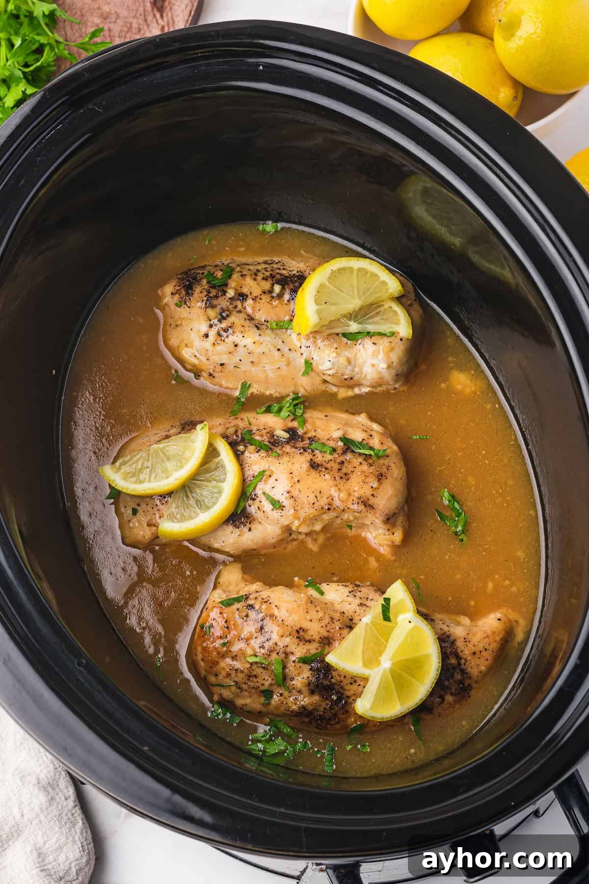 Slow cooker filled with lemonade chicken, ready to serve.