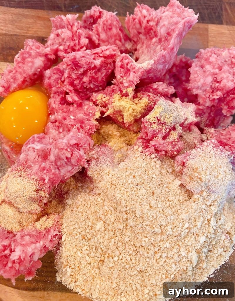 Large glass bowl with ground 50/50, bread crumbs, eggs, seasonins and milk to make meatballs.