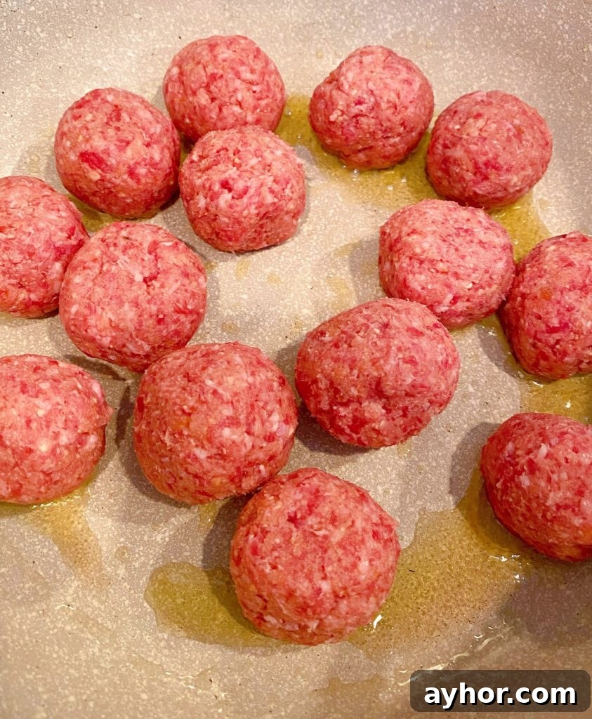 Meatballs in large pot browning.