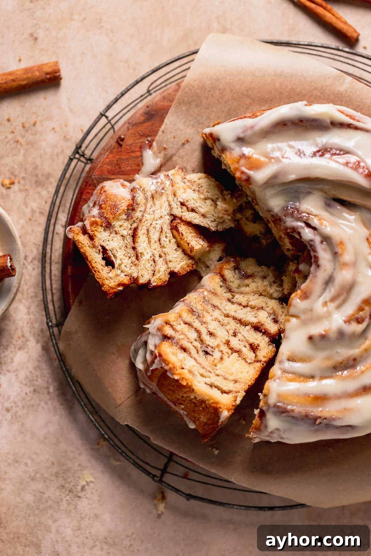 Cinnabon-Style Cinnamon Roll Cake Recipe 2 Cinnamon roll cake slices on a wooden cake board on their side to show the cinnamon swirl texture.
