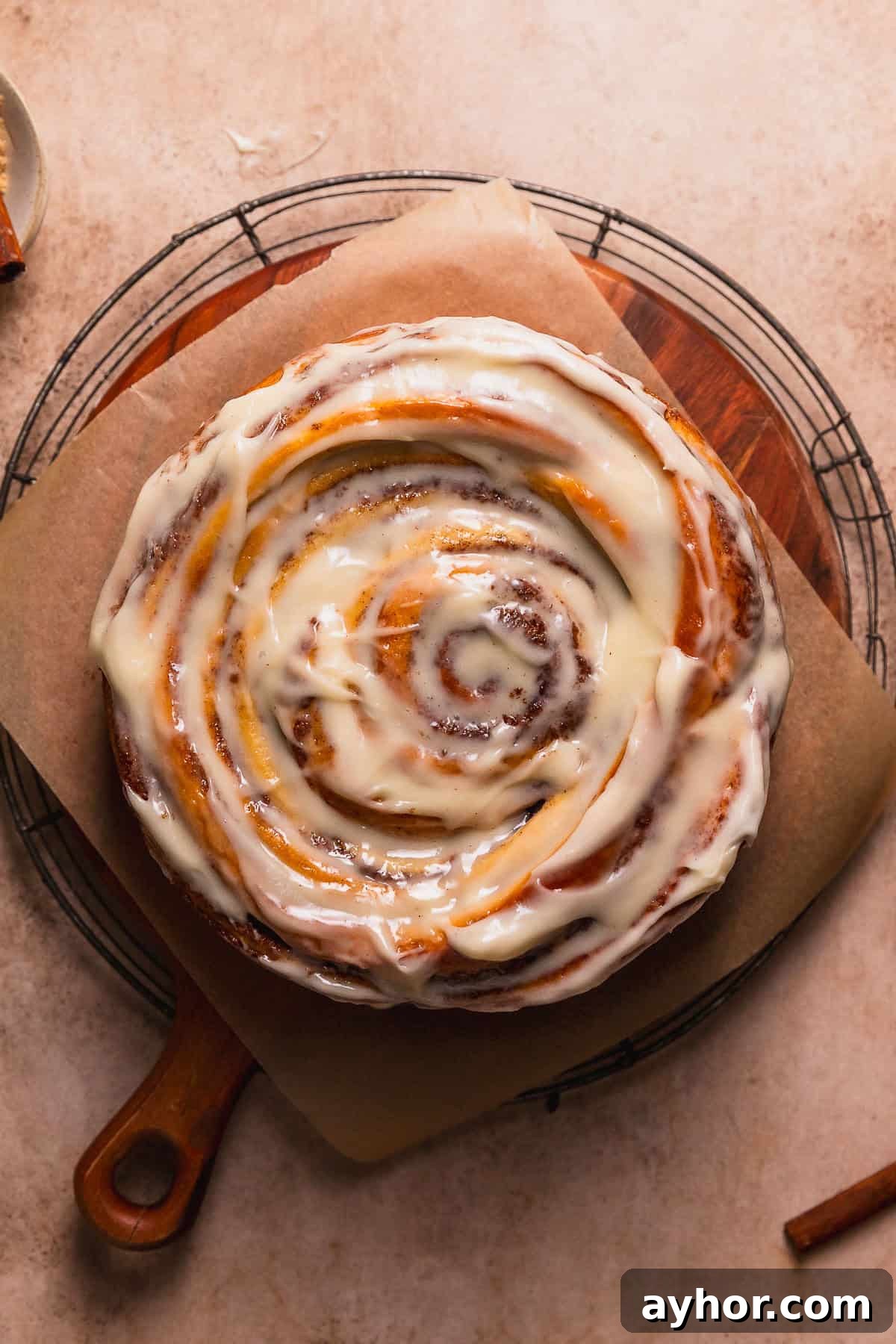 Cinnabon-Style Cinnamon Roll Cake Recipe 12 Cinnamon swirl cake on a wooden platter after being frosted.
