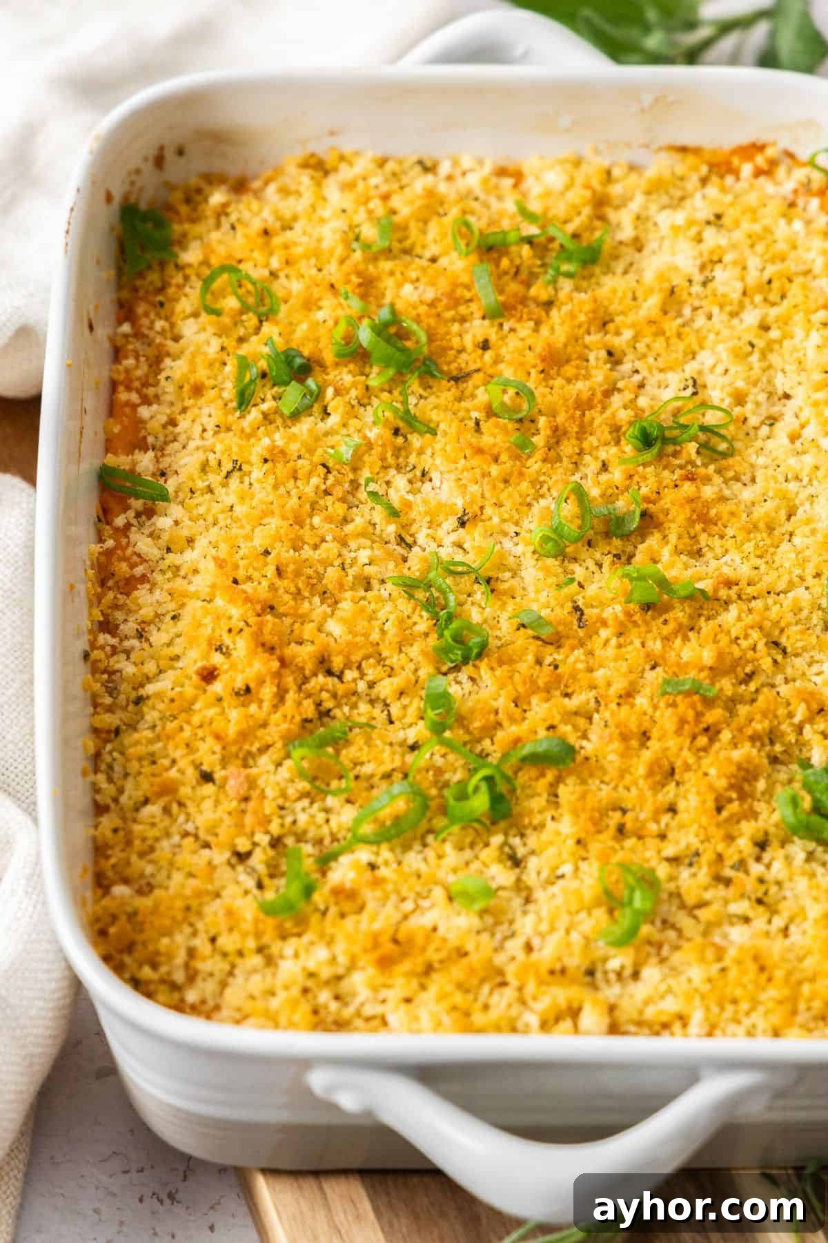 White rectangular baking dish, sitting on a wooden board, containing Baked Mashed Sweet Potato.