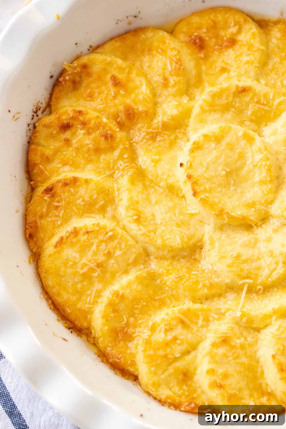 Round white dish of Gnocchi alla Romana, sitting on a blue and white striped tea towel.