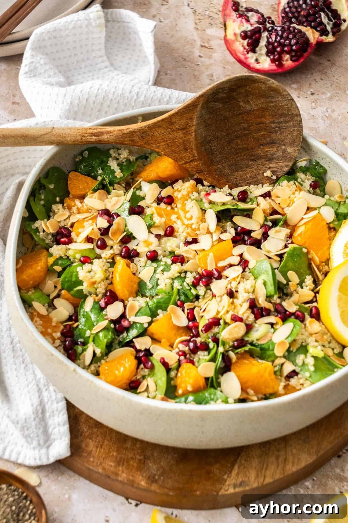Round cream dish of Quinoa and Spinach Salad, with a wooden serving spoon sitting on the edge.