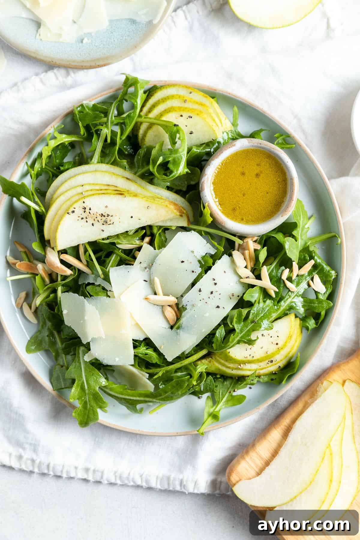 Plate with salad and a pot of dressing on the side.