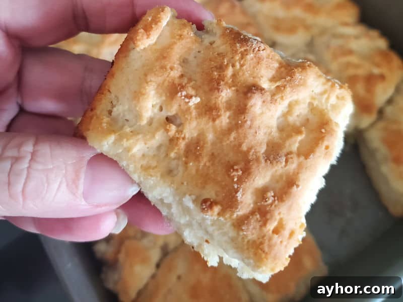 Flaky 7-Up Biscuits Recipe with How-To Video 4 7 Up biscuit being held above a pan of biscuits