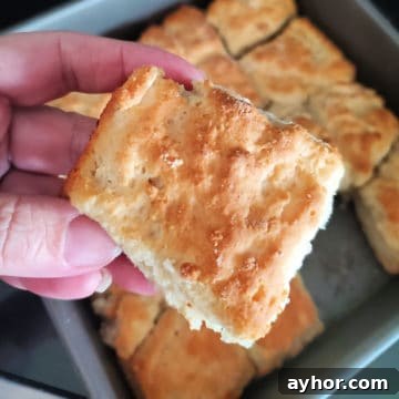 Flaky 7-Up Biscuits Recipe with How-To Video 5 7 Up biscuit being held above a pan of biscuits
