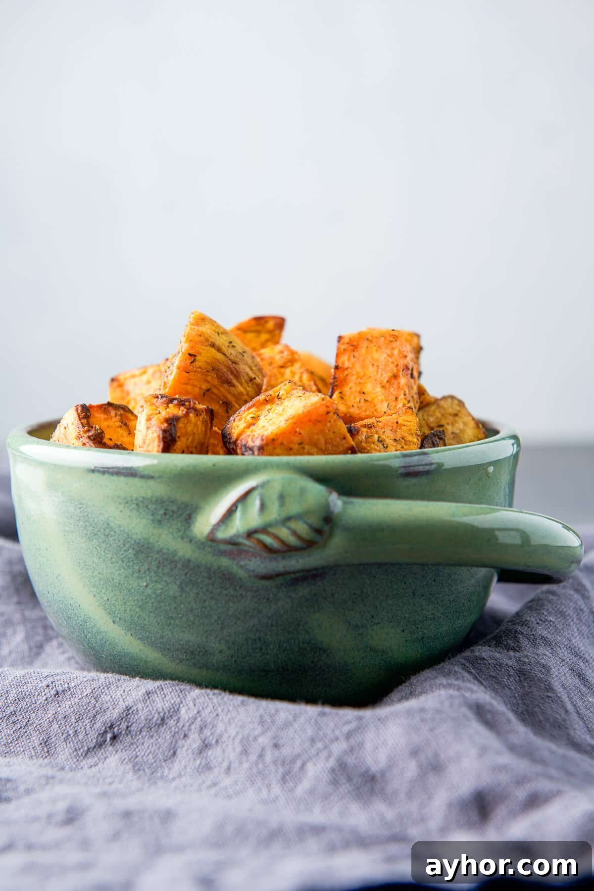 vertical view of a green bowl of sweet potatoes