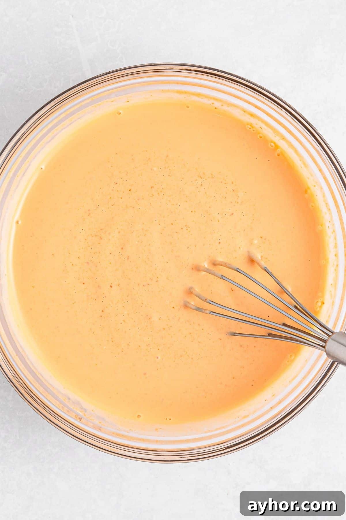 Sriracha Aioli Recipe (Gluten-Free, Dairy-Free) Whisking sriracha aioli in glass bowl.
