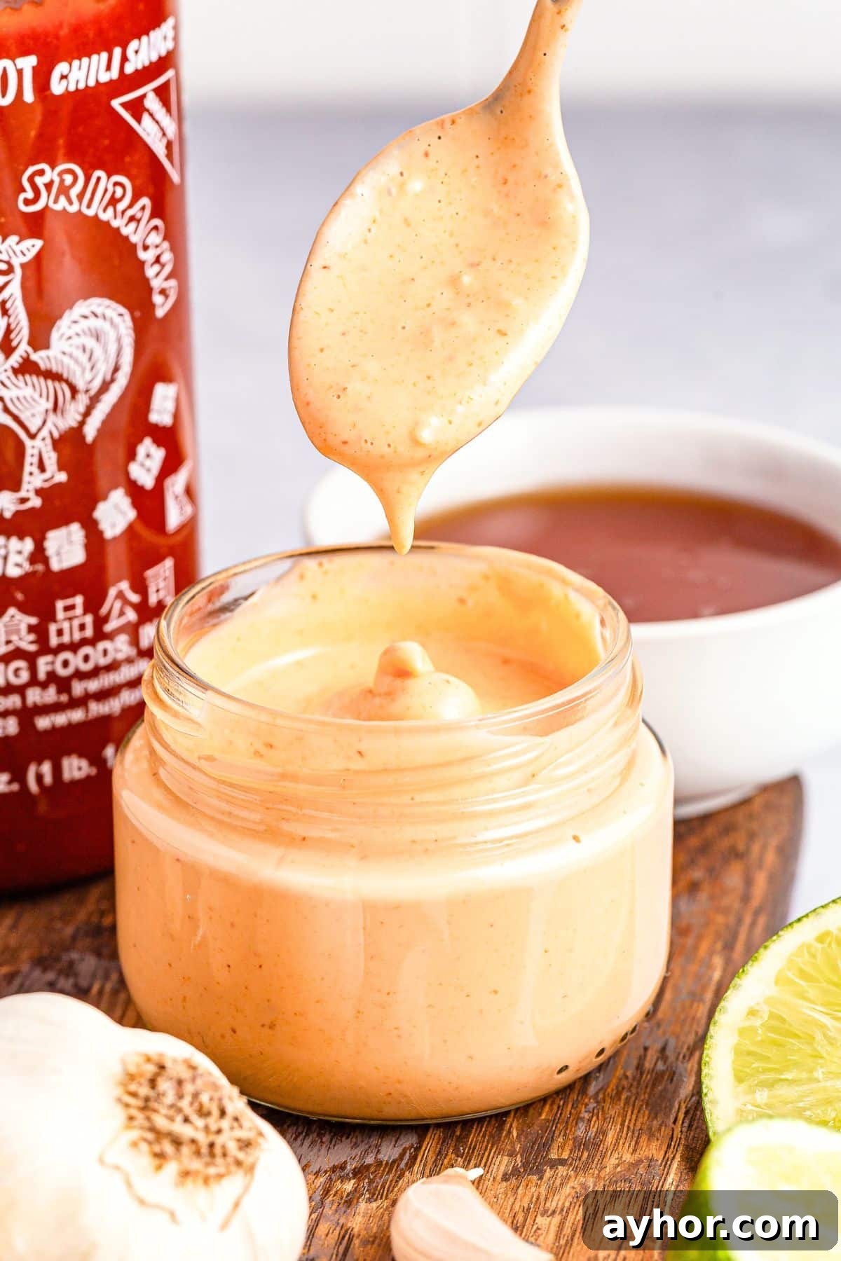 How to Make Sriracha Aioli (Gluten-Free, Dairy-Free) Drizzling sriracha aioli into a jar.