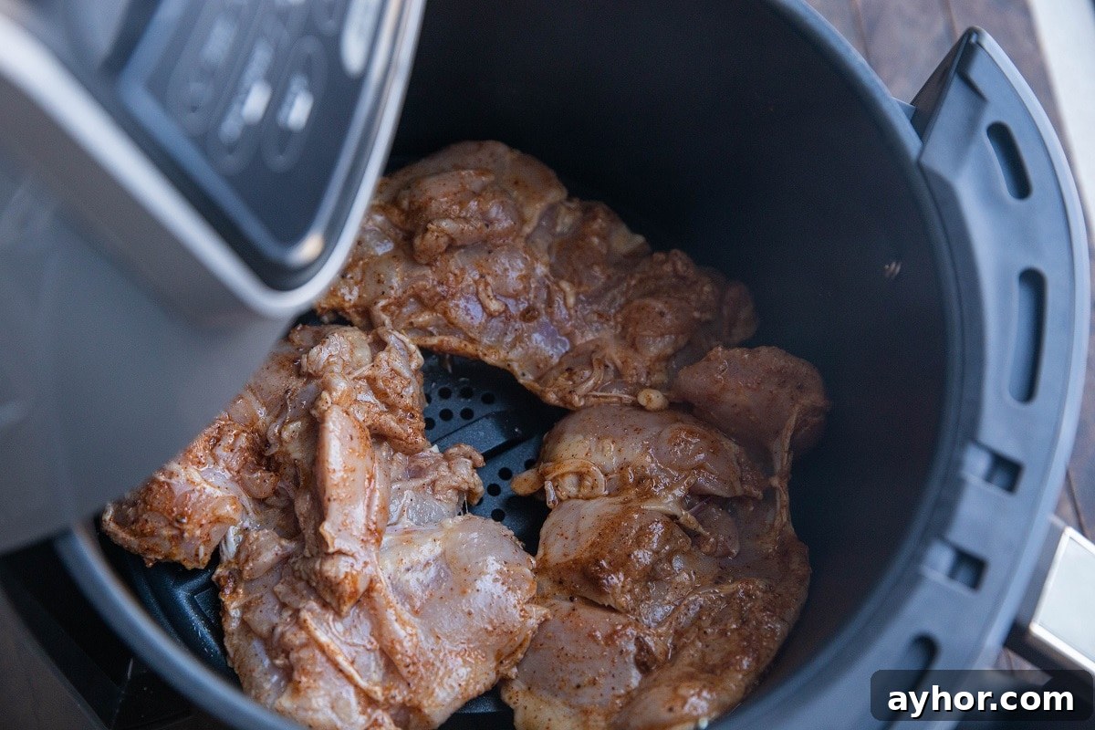 Crispy Mediterranean Chicken Thighs in the Air Fryer 7 Chicken thighs in an air fryer, ready to air fry.