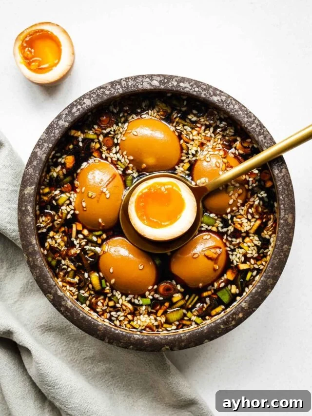 Gochujang Braised Tofu: Spicy Korean Tofu Recipe 12 Mayak eggs in a ceramic bowl with one egg sliced in half to show the jammy egg centre.