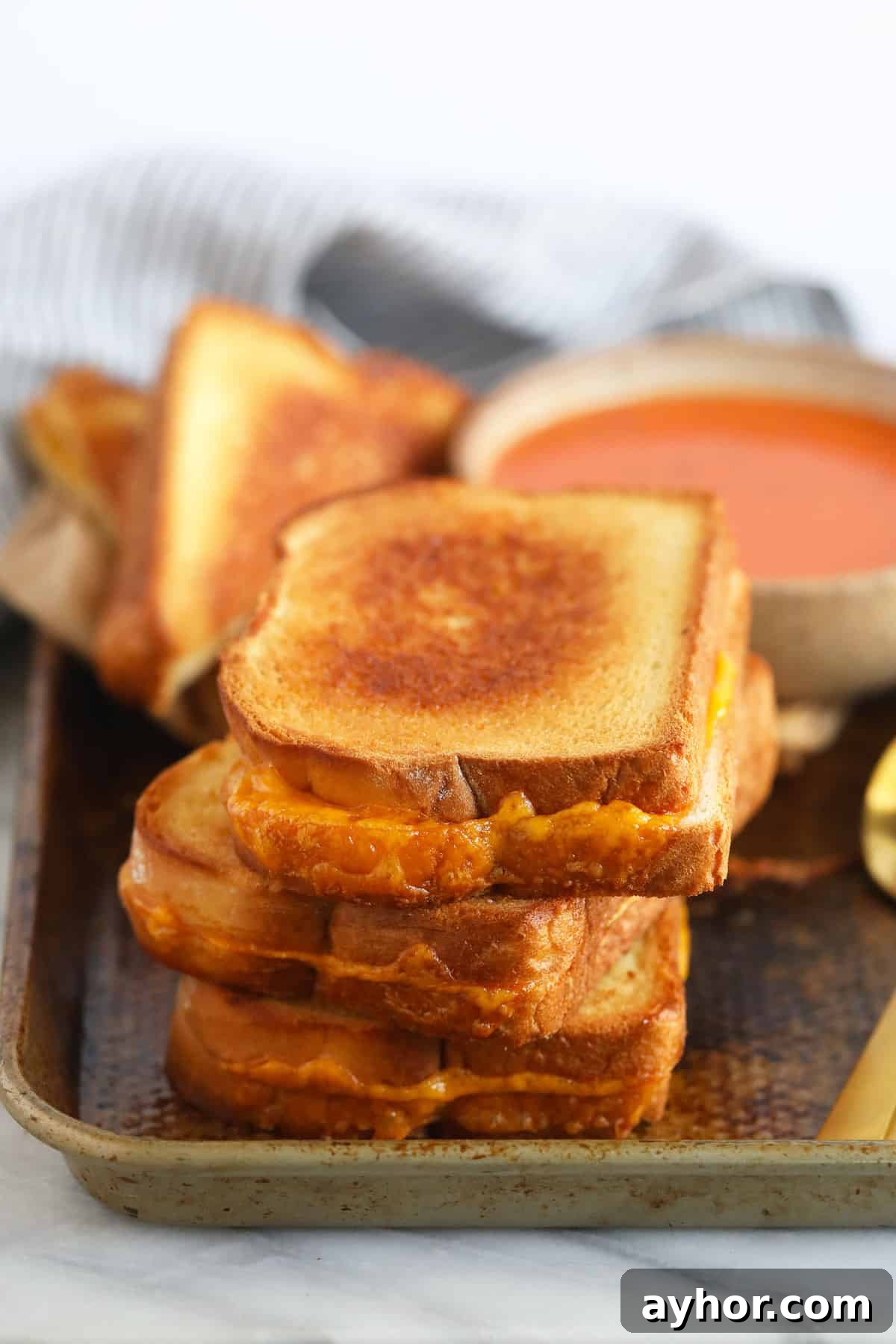 Sheet Pan Grilled Cheese sheet pan grilled cheese sandwiches next to a bowl of tomato soup